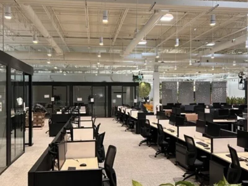 Showroom floor with rows of workstations under warehouse-style ceiling